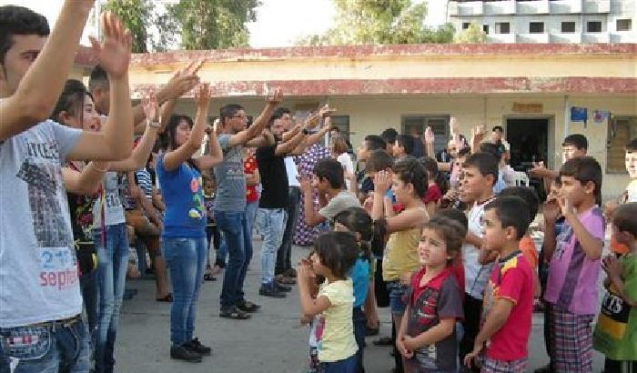 Cooperanti giocano con i bambini in fuga dall'Isis