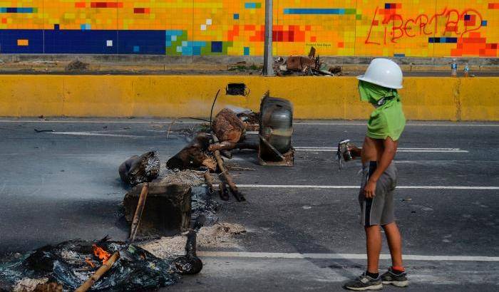 Un manifestante in piedi di fronte un blocco contro la protesta anti-Maduro