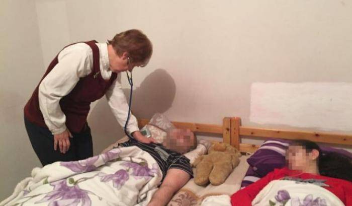 Kostan e Milena, nel letto della loro casa, assistiti da un medico